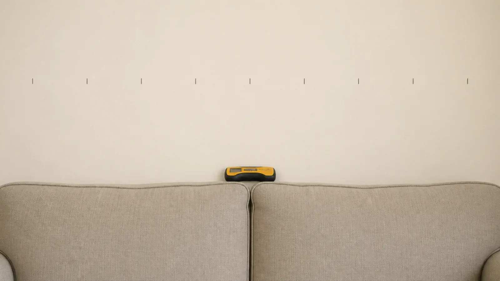 row of pencil stud marks spread across a bare sofa wall