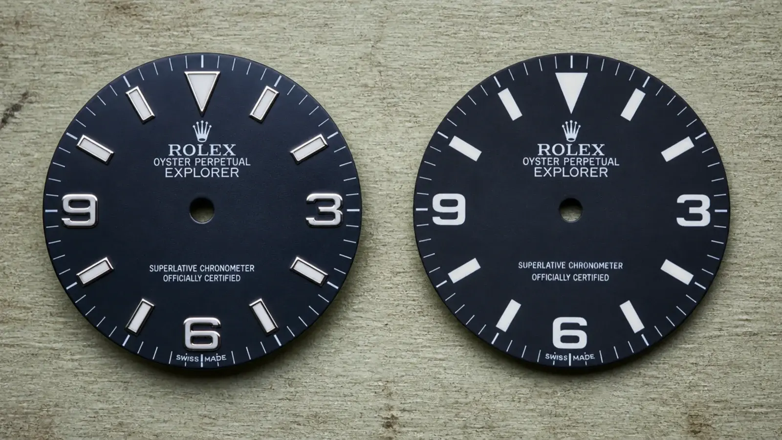 two clock dials compared side by side on a workbench surface