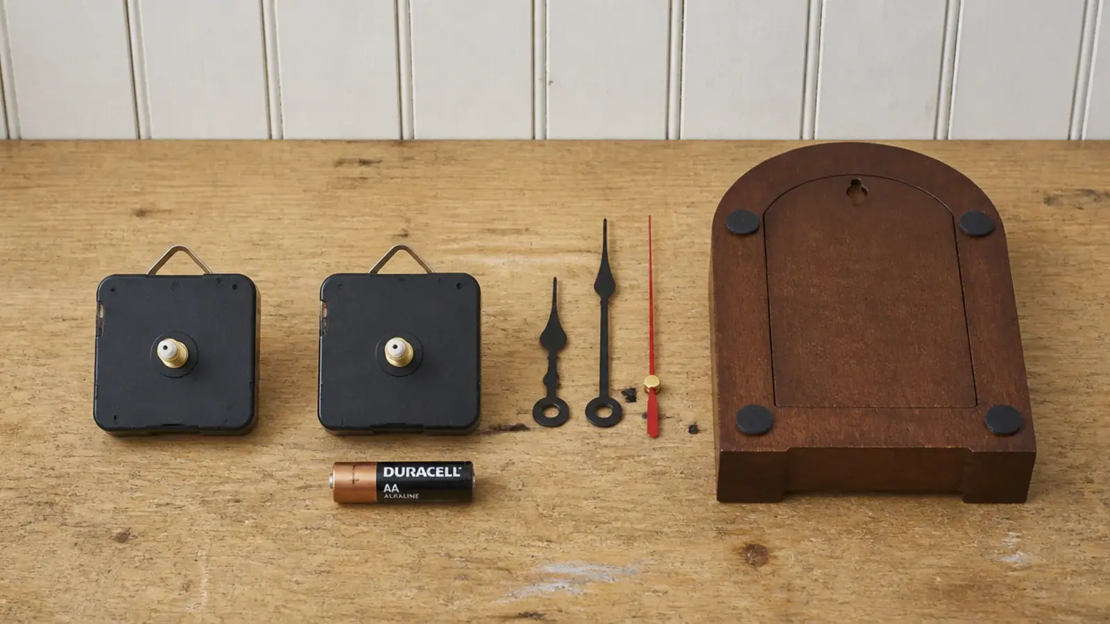 two quartz movements laid out beside a clock case and battery