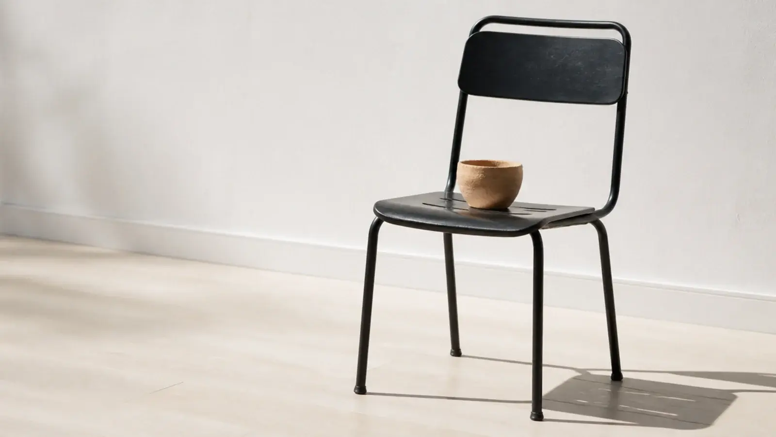 black metal chair standing alone on a very pale timber floor