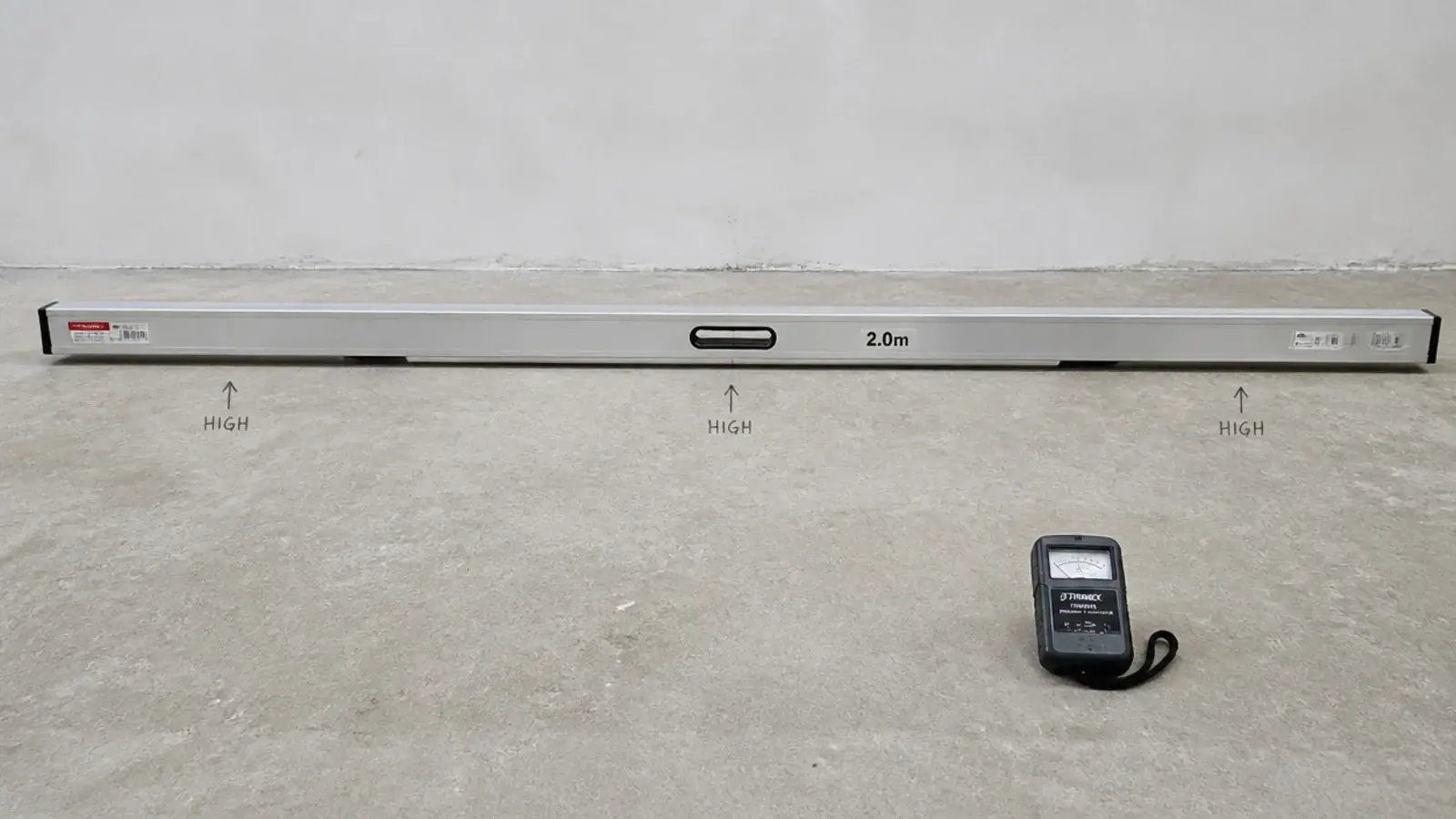 straightedge and moisture meter checking a bare concrete subfloor surface