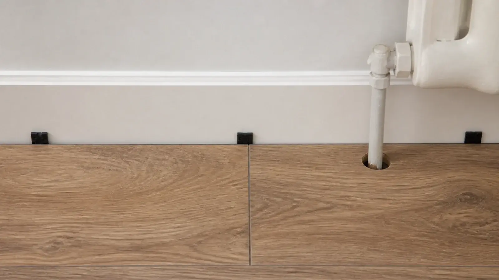 small perimeter gap held open between vinyl planks and a bedroom wall