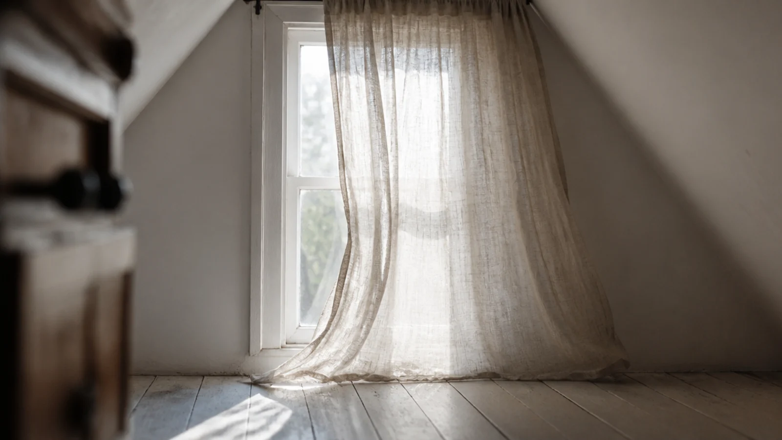 unlined linen curtain filtering daylight on an attic gable window
