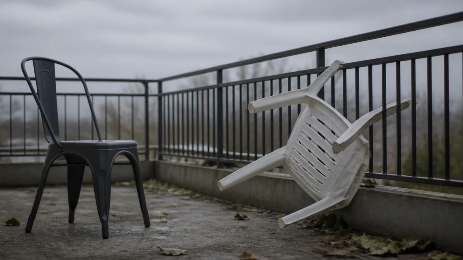 lightweight plastic chair blown against a balcony railing in wind