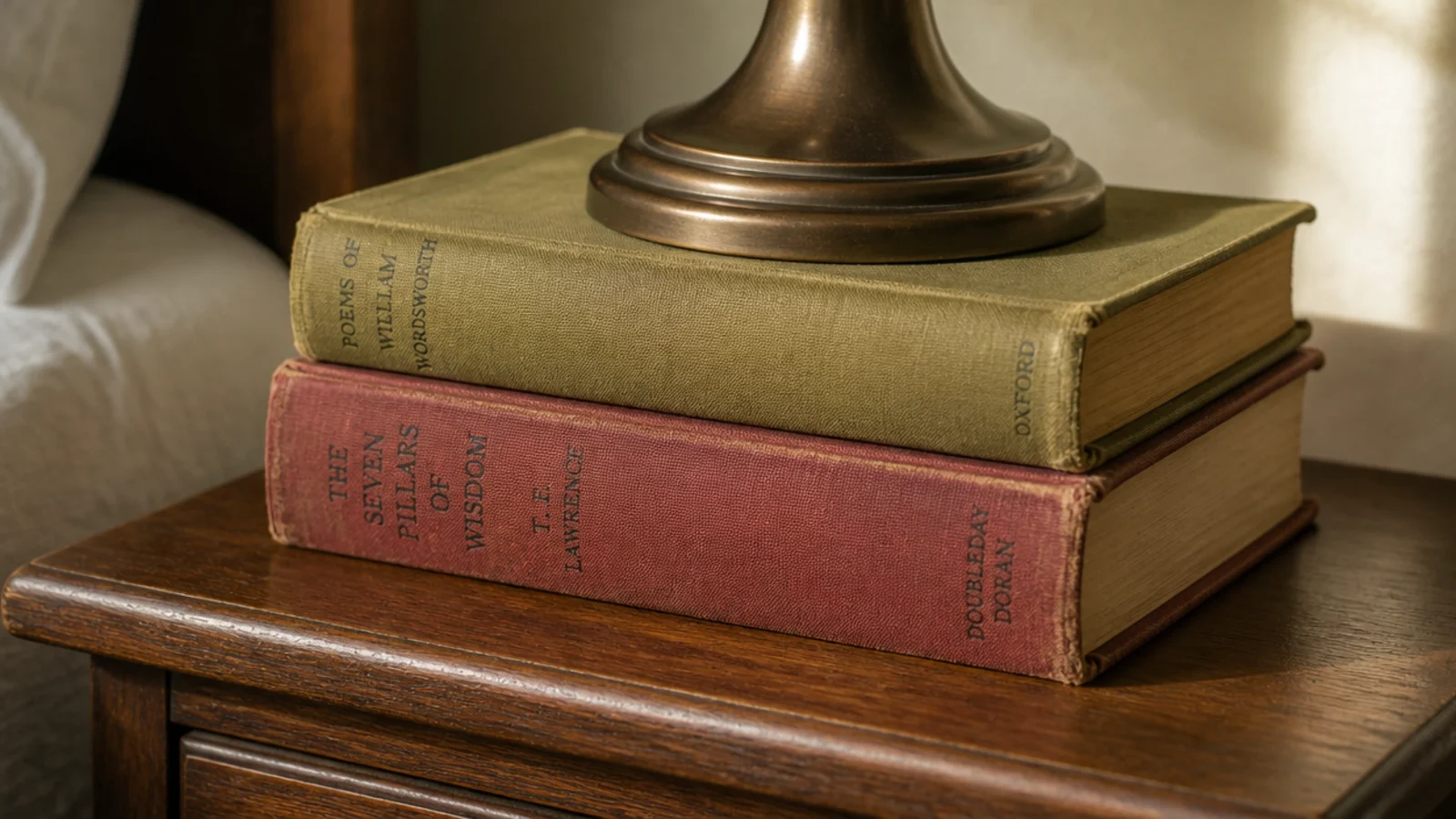 two cloth bound secondhand hardbacks stacked under a small lamp
