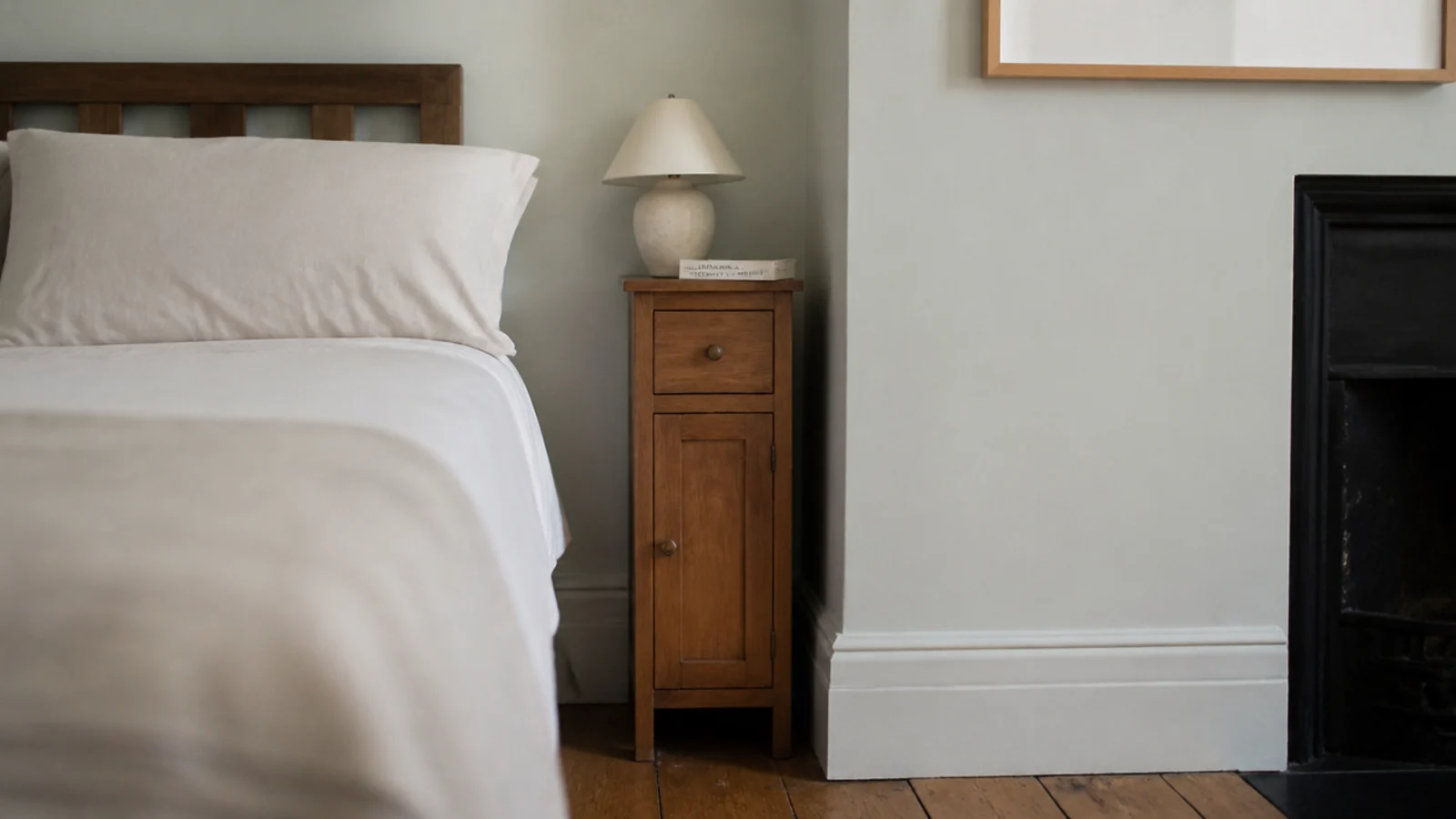narrow bedside table fitted into a slim gap beside a linen dressed bed