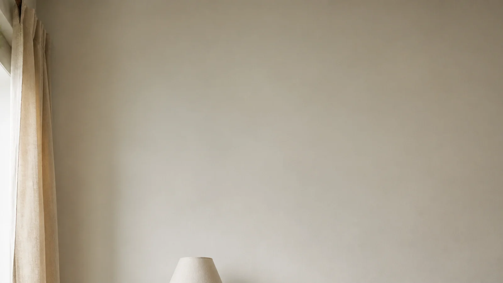 vertical image of a calm bedroom bookshelf beside a linen dressed bed