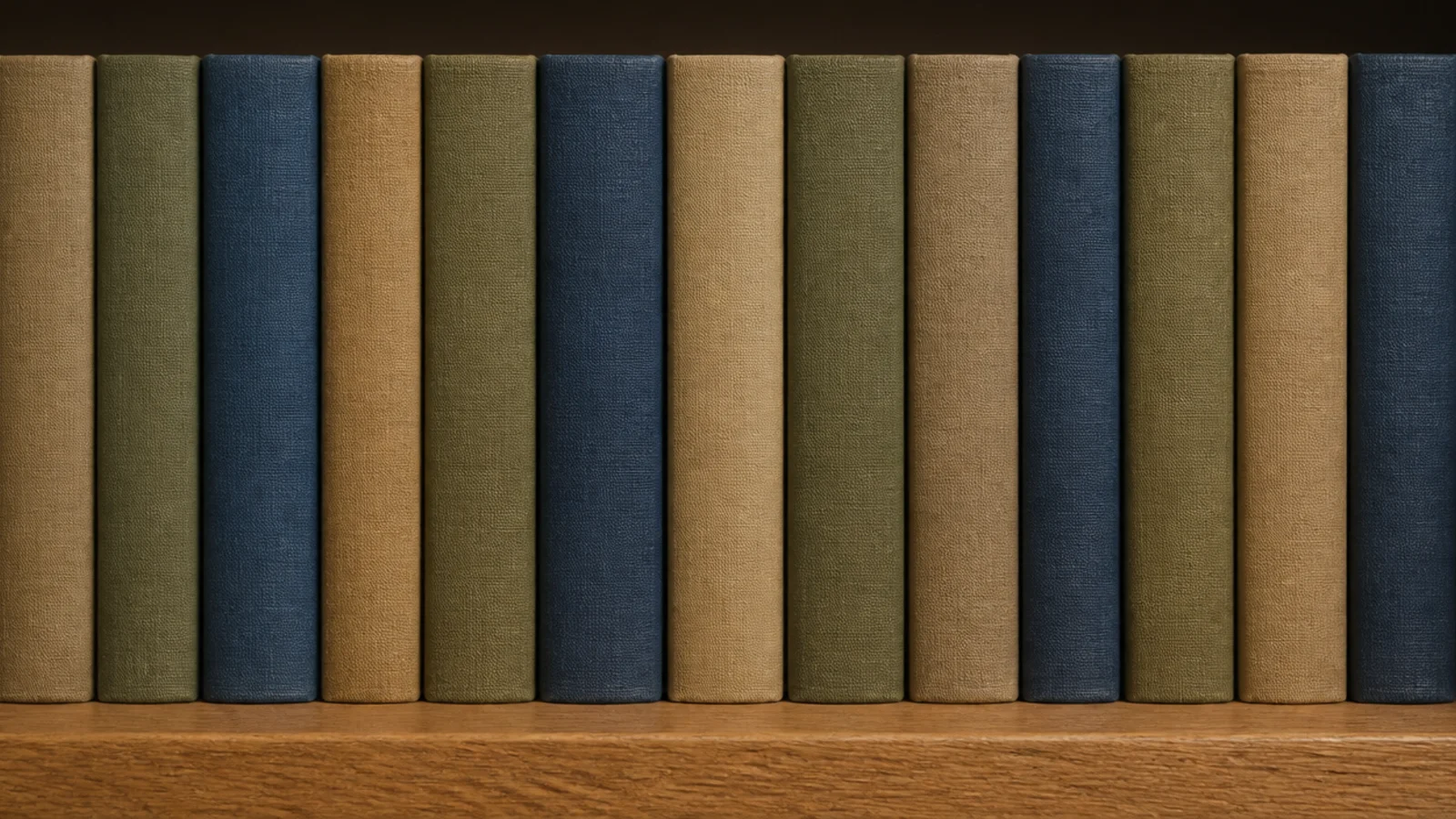 cloth bound book spines in muted tones on a styled bookshelf