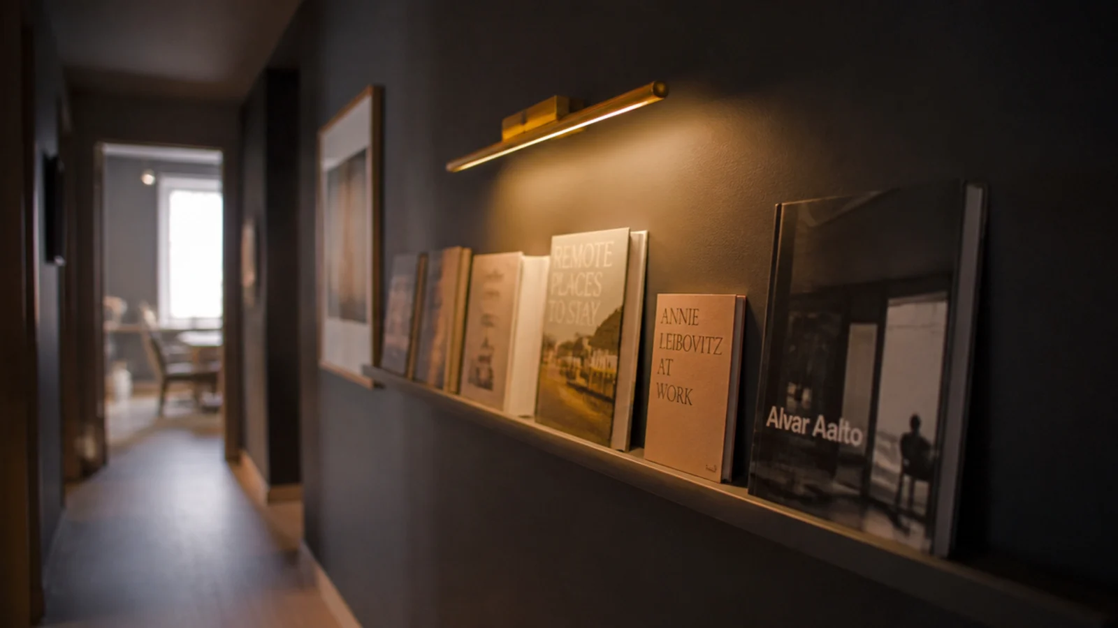 hallway book ledge lit by a small brass picture light above it