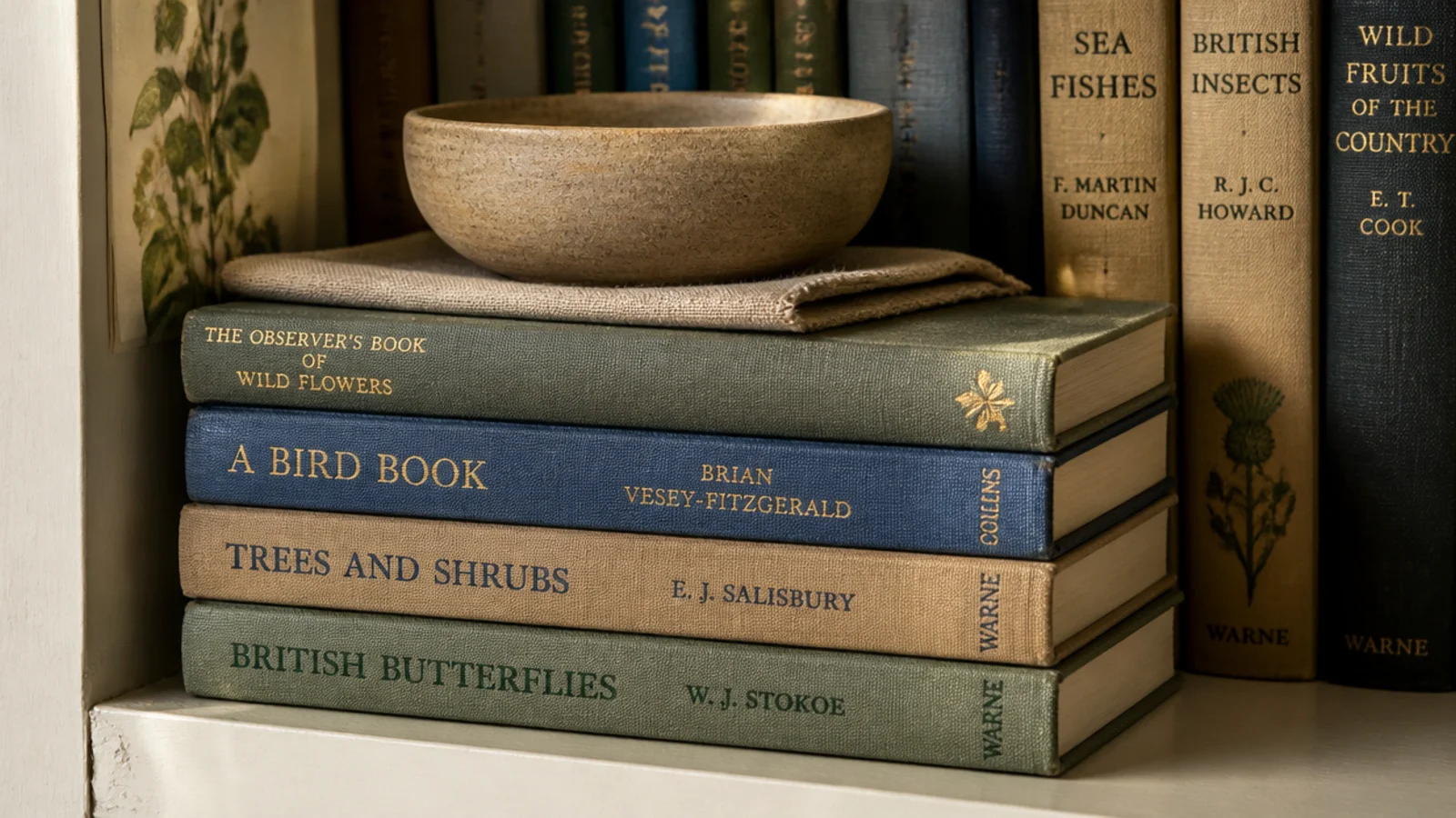 three hardbacks laid flat as a pedestal under a small clay bowl