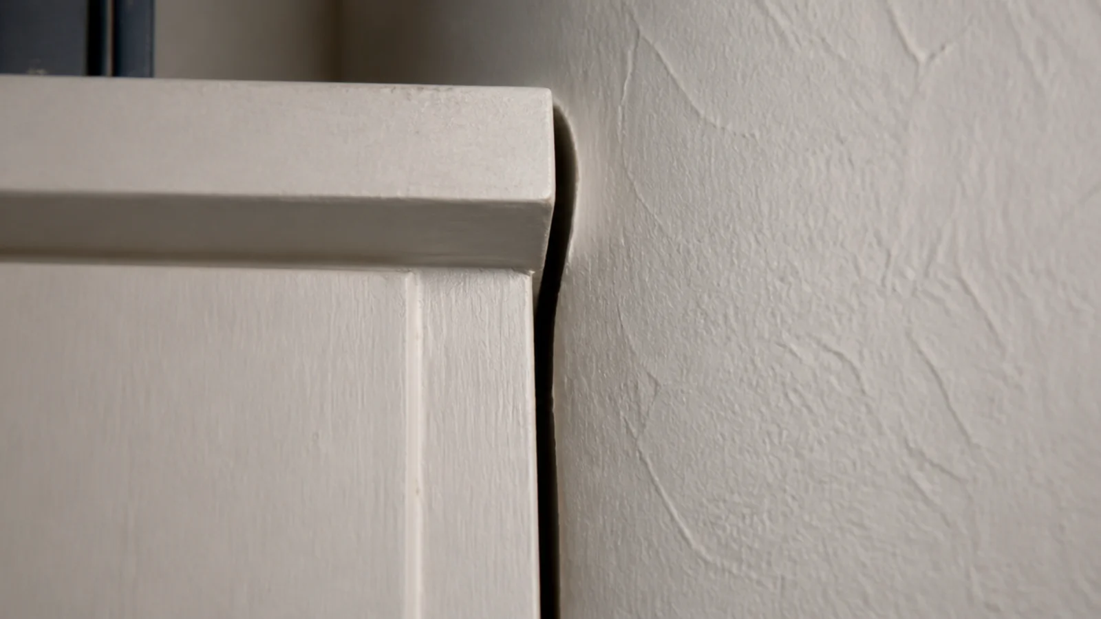 visible shadow gap between built-in shelving and an uneven plaster wall