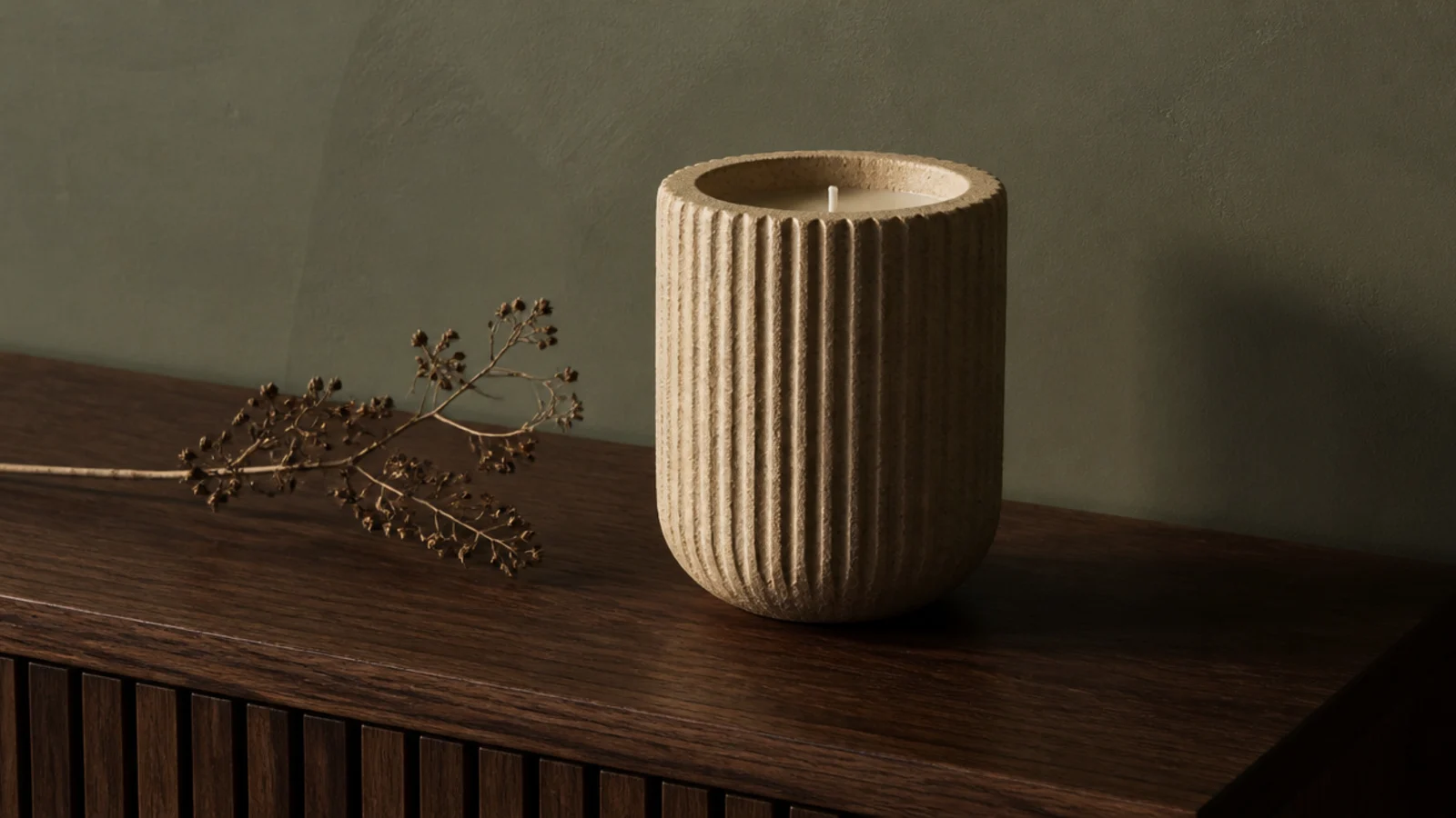 ribbed stoneware vessel candle catching raking light on a walnut surface