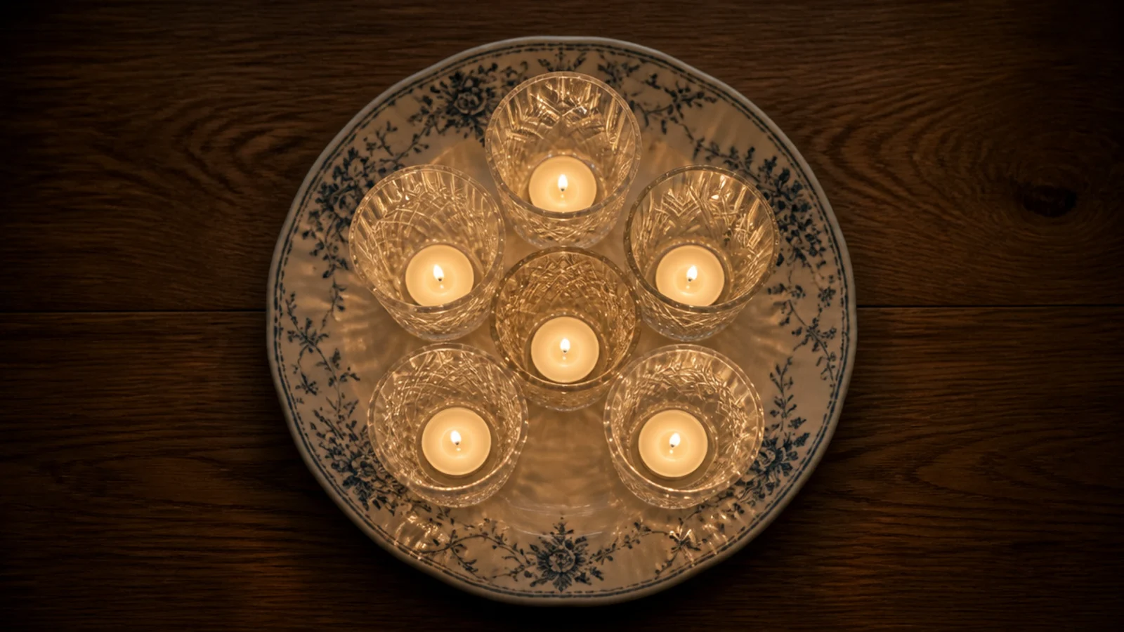 tealights glowing inside mismatched vintage drinking glasses on a plate