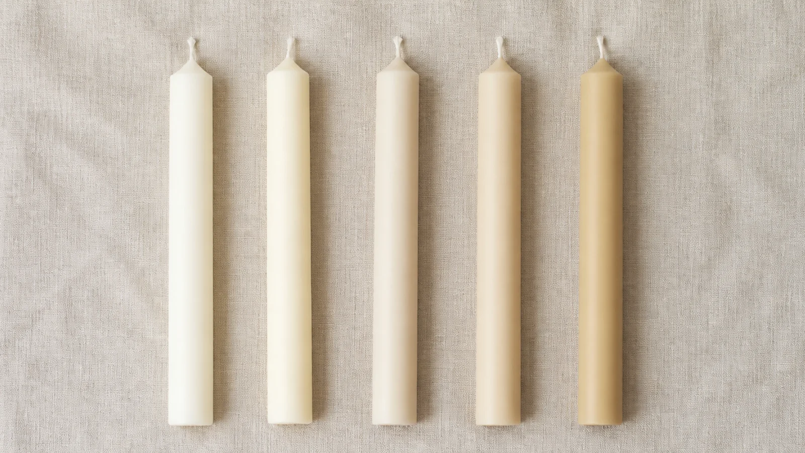 row of cream ivory and sand candles compared side by side on linen