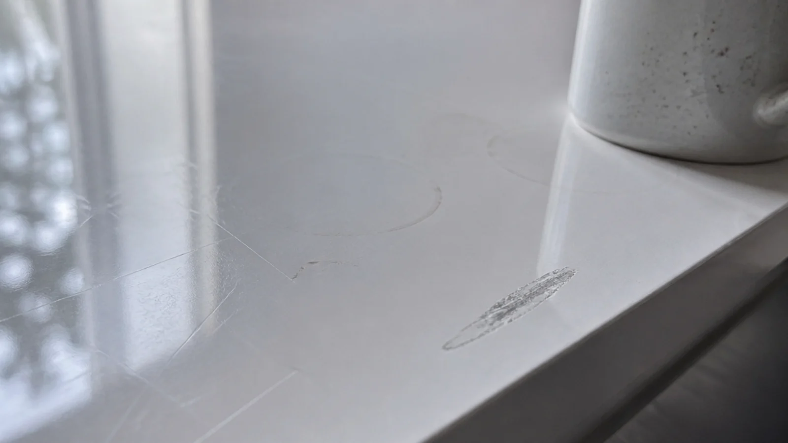 white gloss table surface showing rings scuffs and a hairline scratch