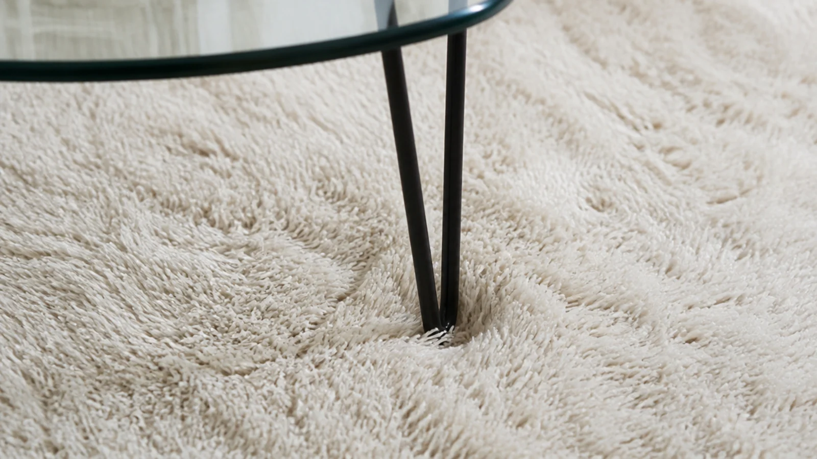 thin hairpin leg sinking into a thick wool pile rug surface