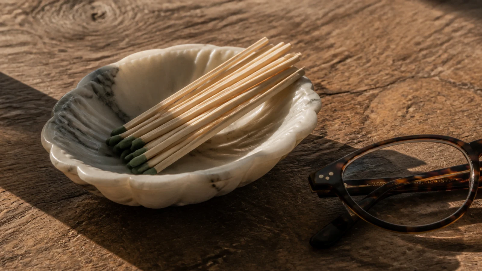 tiny stone dish holding matches beside a folded pair of glasses