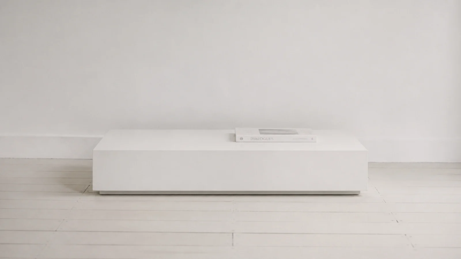 plinth table painted the same soft white as the wall behind it