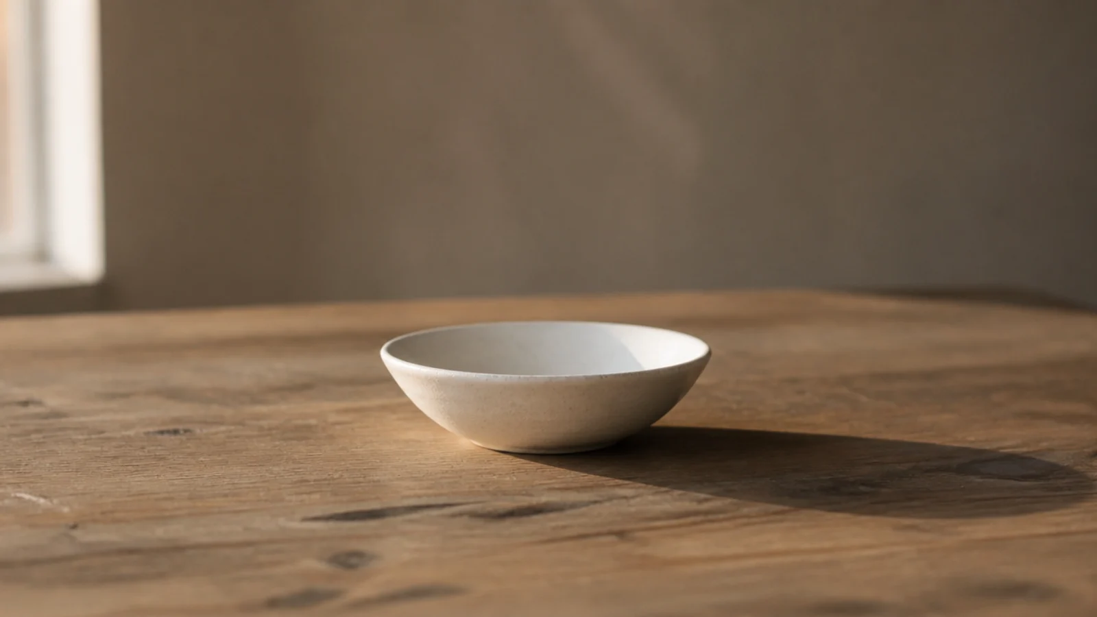 one wide shallow bowl alone at the centre of a bare table