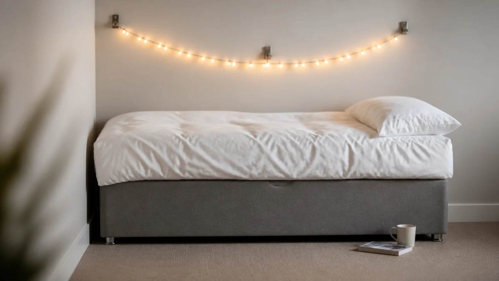 warm strand arcing over a plain divan bed on three clips