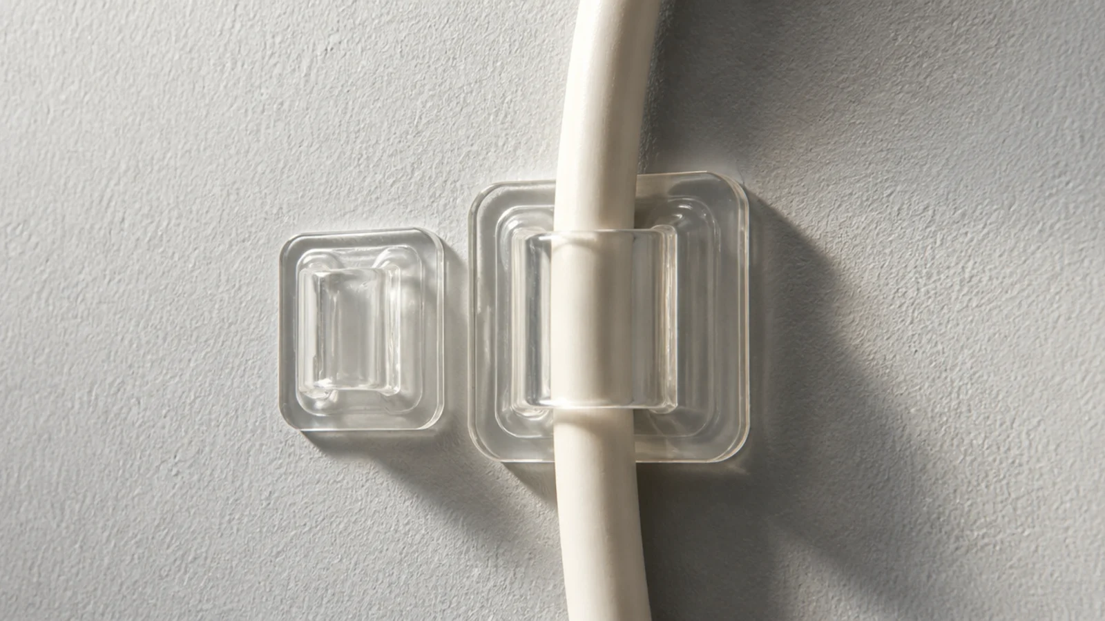 two sizes of adhesive clip compared on a painted wall
