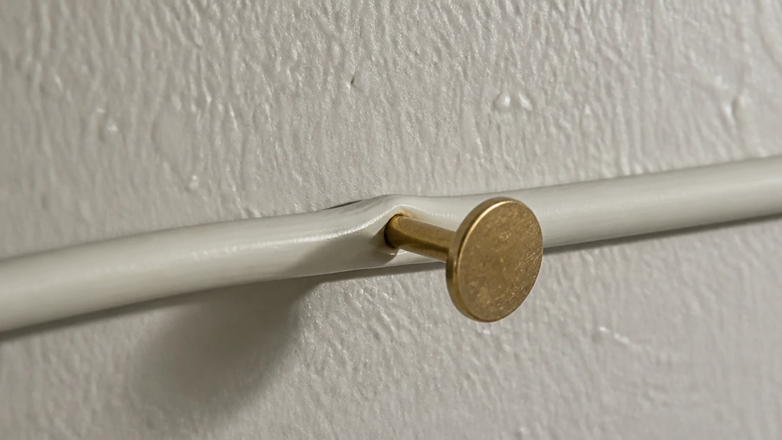 drawing pin pushed through a light cable against a wall