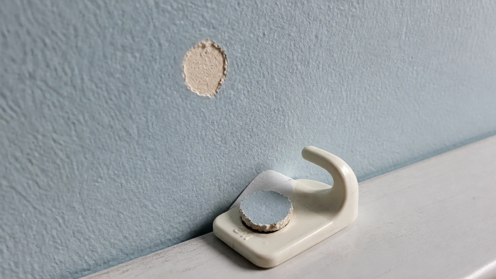 small patch of paint lifted from a wall by a removed clip