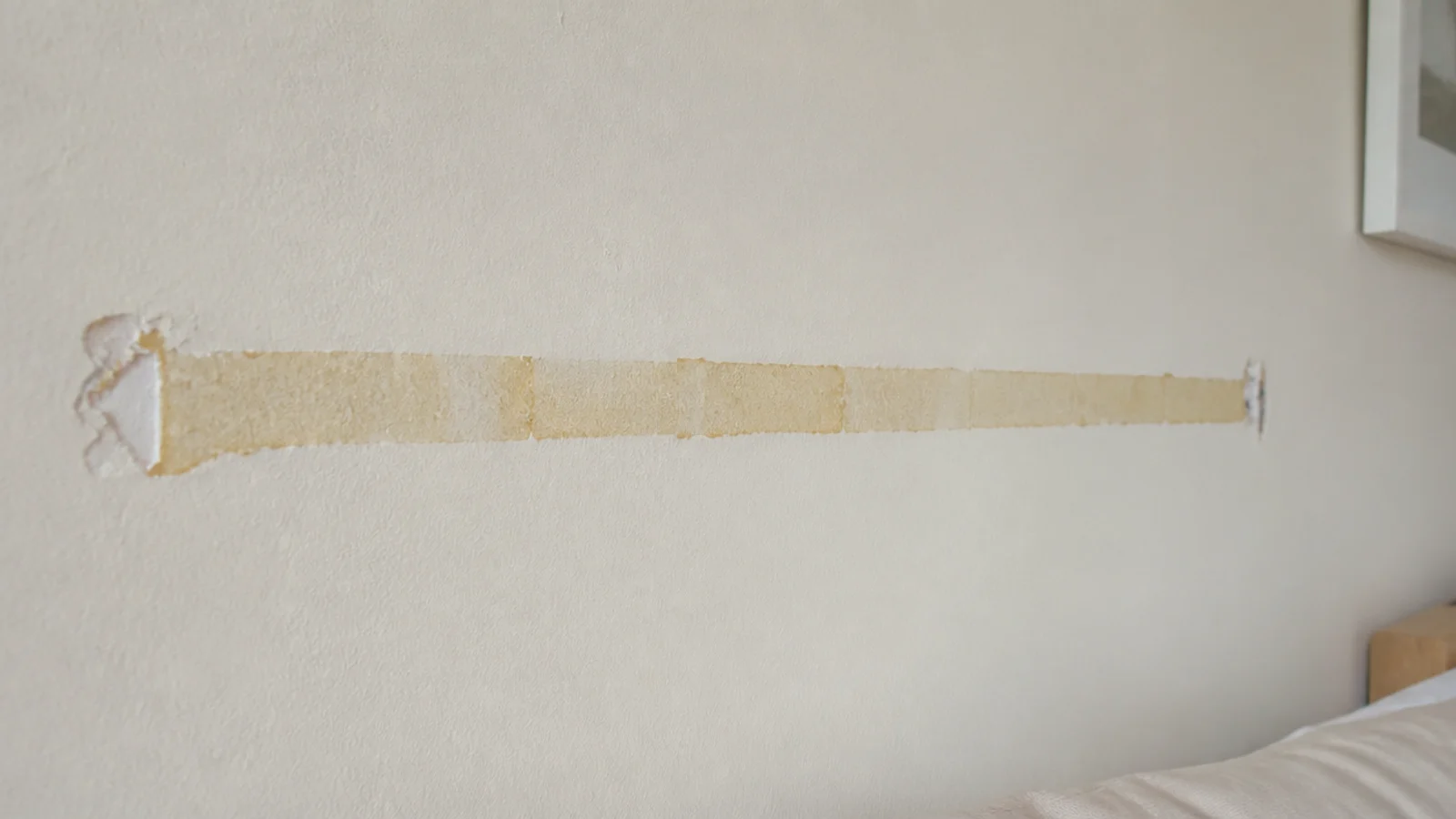 yellowed tape residue left on a wall after removing a strand