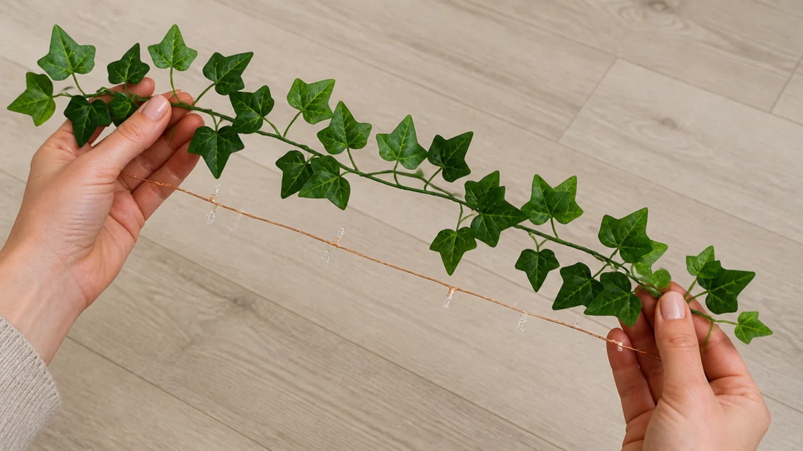 hands measuring a length of ivy garland against a light strand