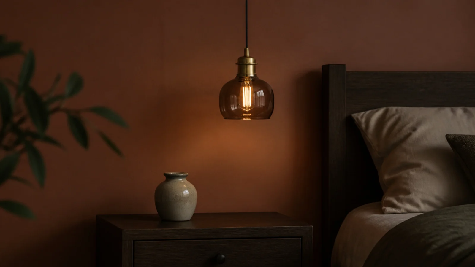 smoked glass pendant with brass fittings against a deep painted wall