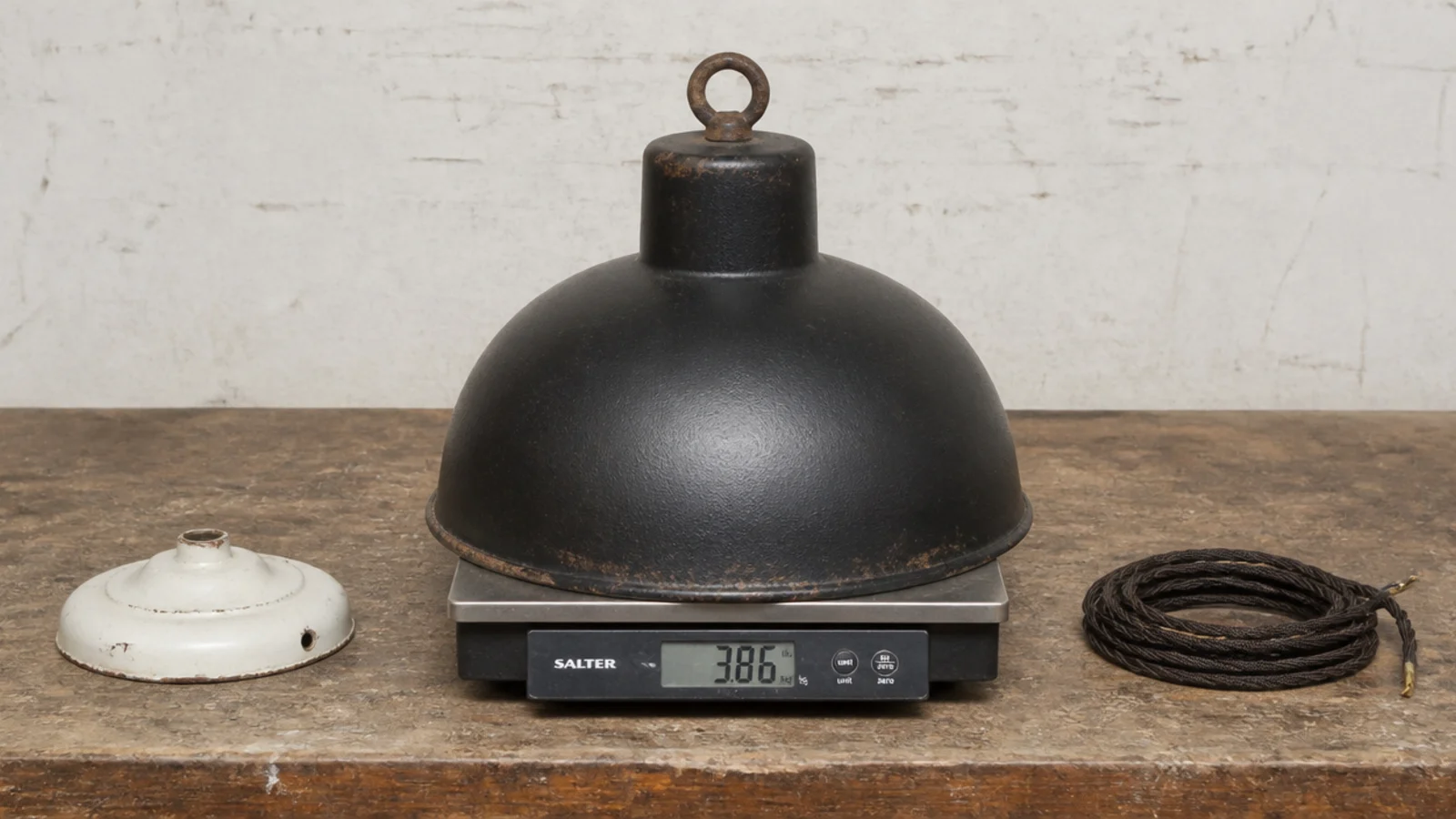 heavy iron shade resting on scales beside an old ceiling rose
