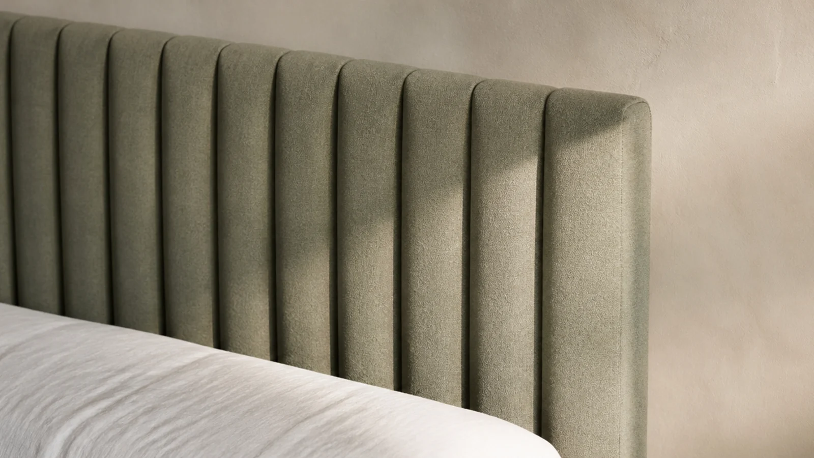 vertical channel tufted headboard in muted sage fabric with even soft ribs