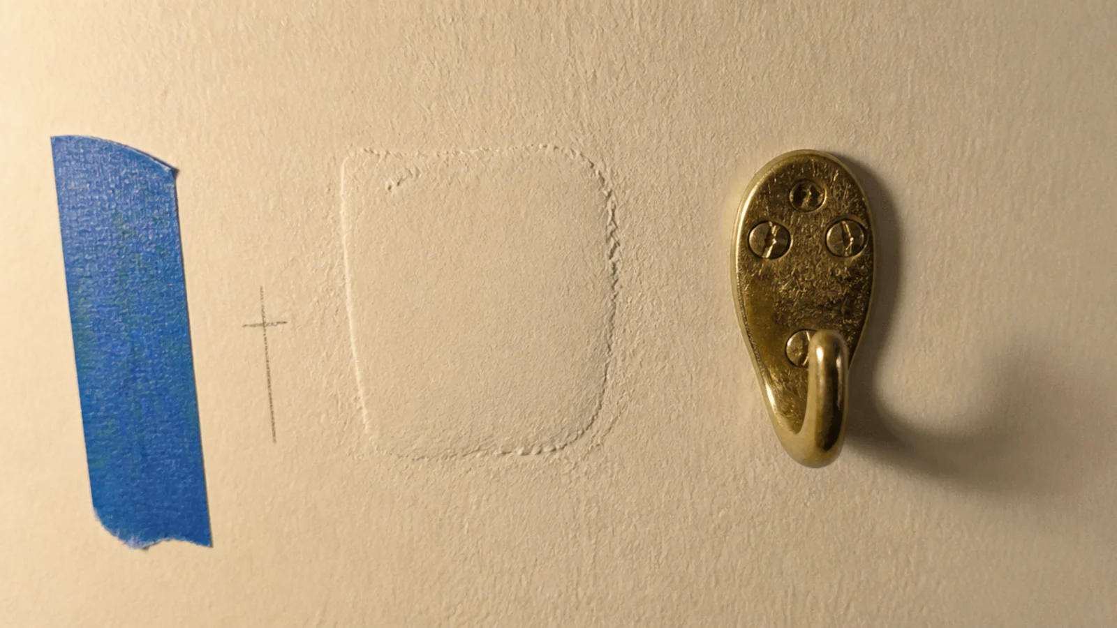 hand feeling an old filled anchor bump on a painted rental wall surface