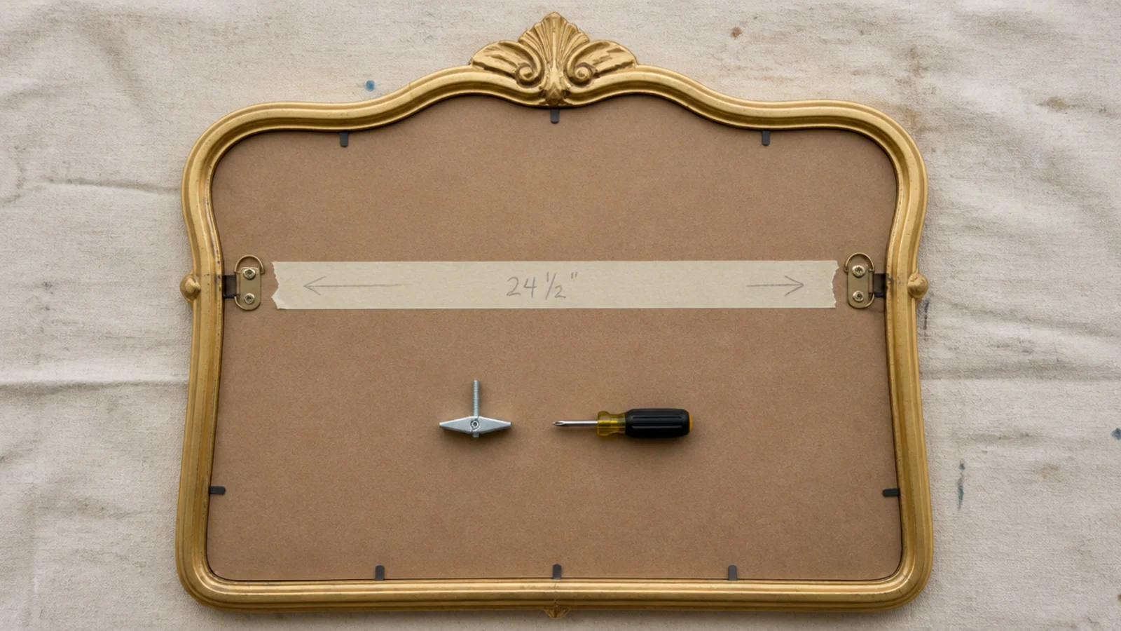 two D-rings and a taped spacing guide on the back of a mirror frame