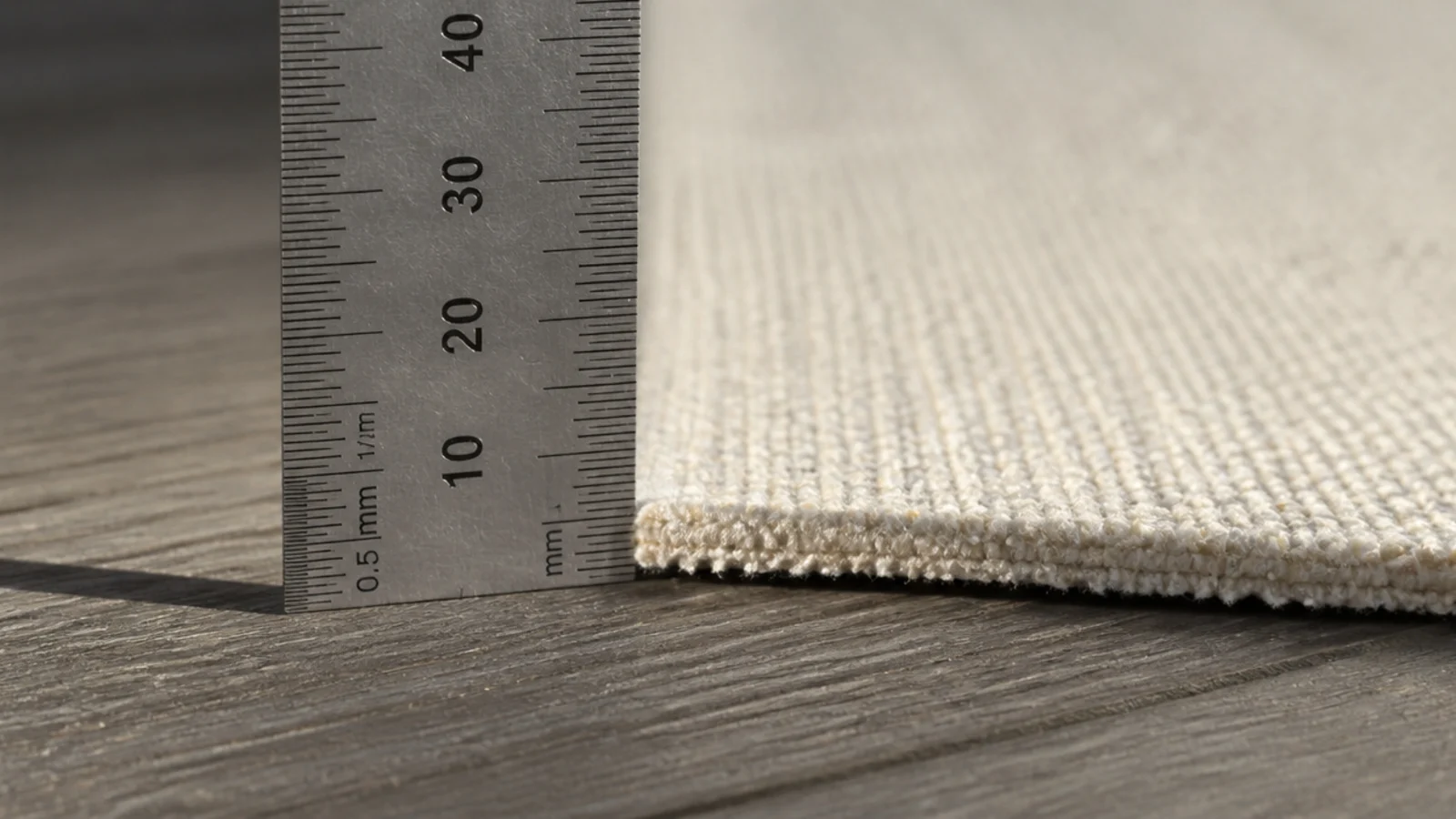 thin flatweave base rug measured against a steel rule for thickness