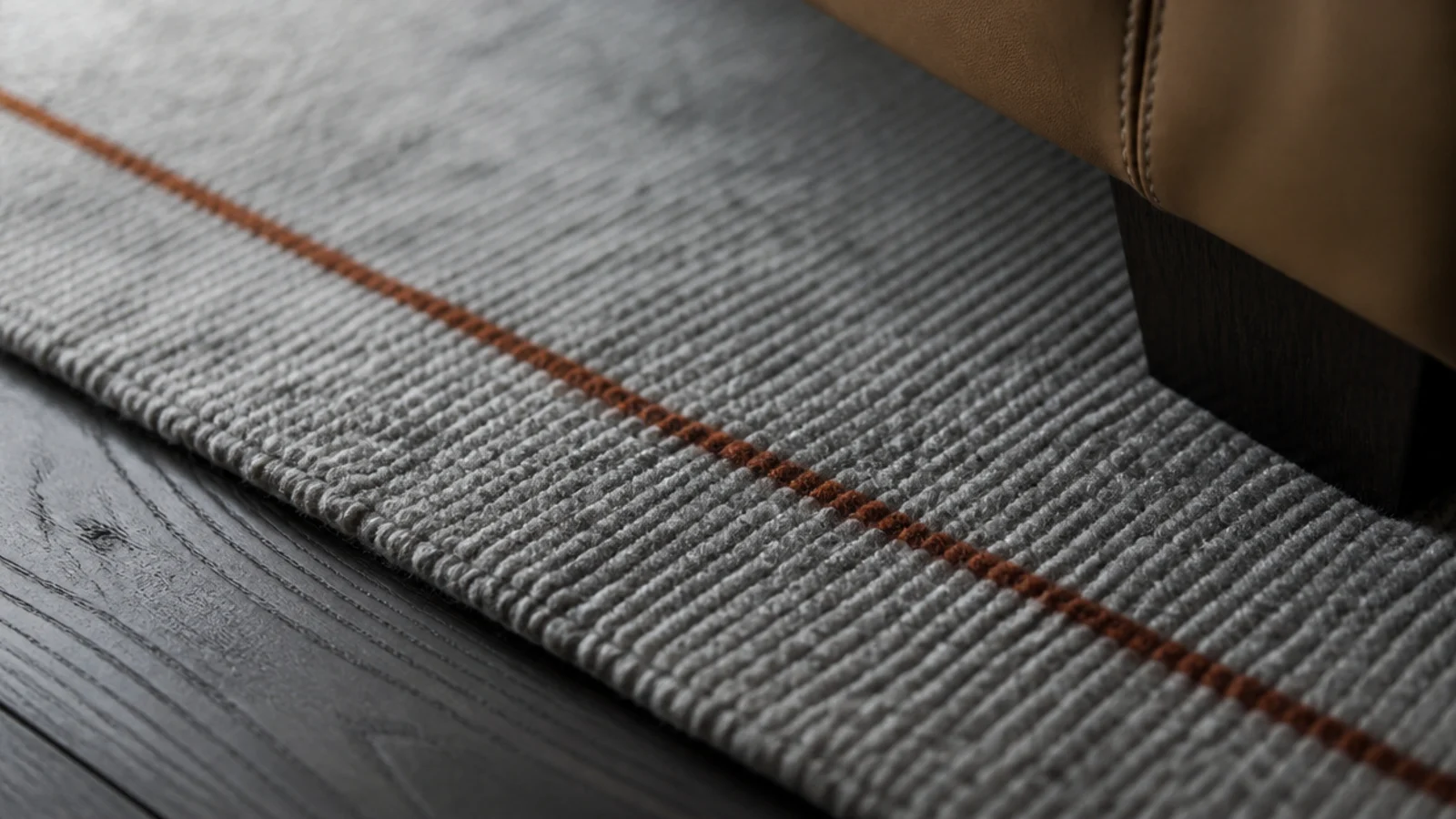 one rust coloured line crossing an otherwise monochrome grey rug