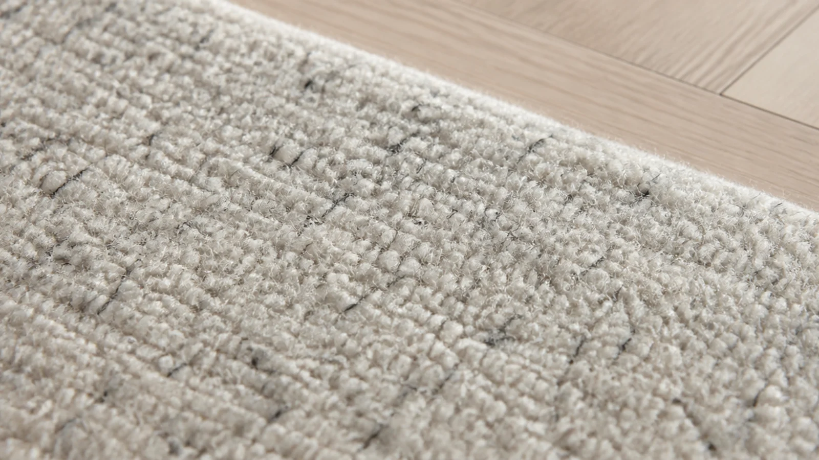 pale wool rug flecked with fine charcoal fibres across the pile
