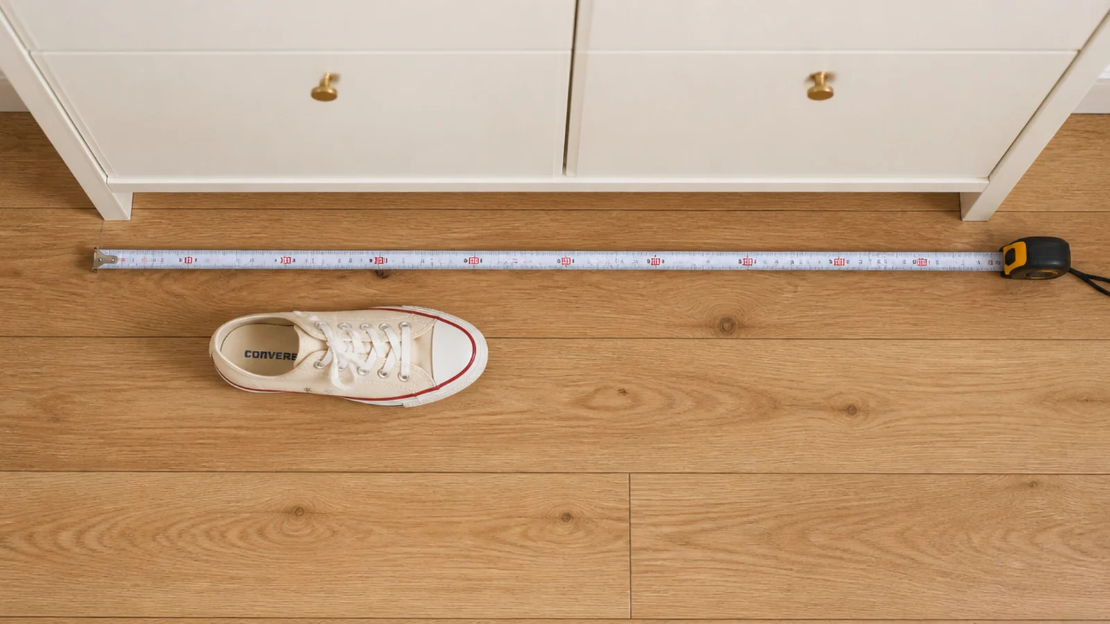 tape measure across a hallway floor beside a slim cream shoe cabinet