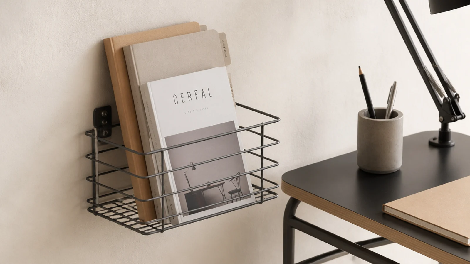 wall mounted paper tray holding folders beside a small desk