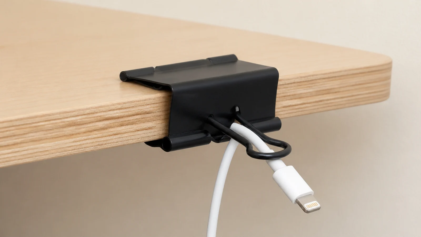binder clip on a desk edge holding a charging cable in place