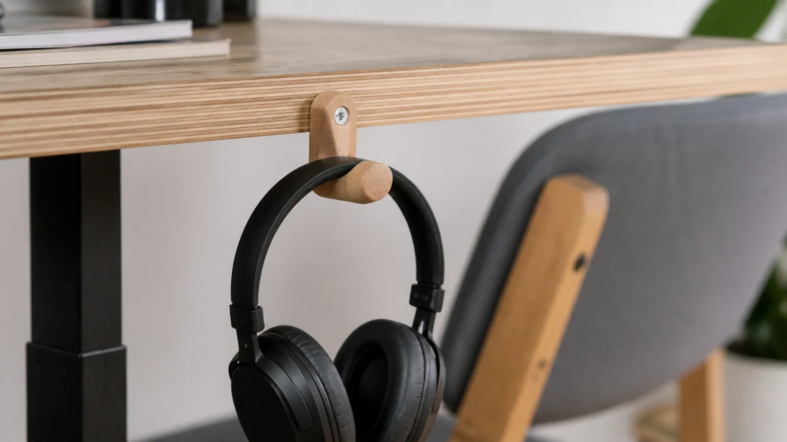 turned wooden peg fixed under a desk edge holding headphones