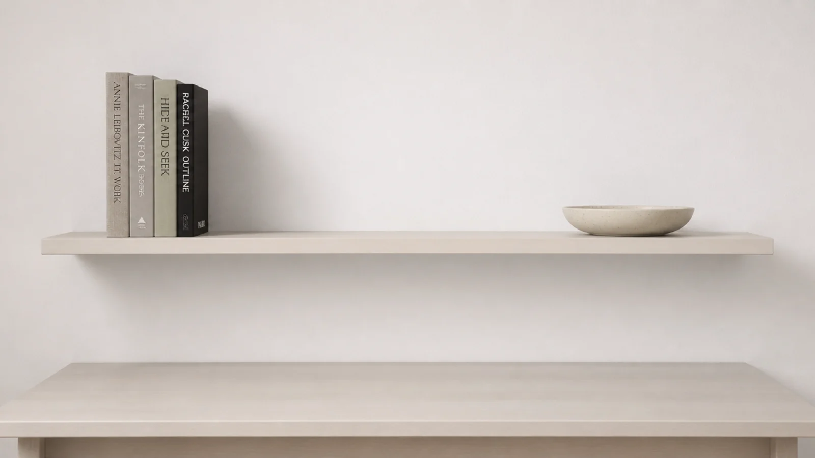 one shelf above a desk with upright books and a flat dish