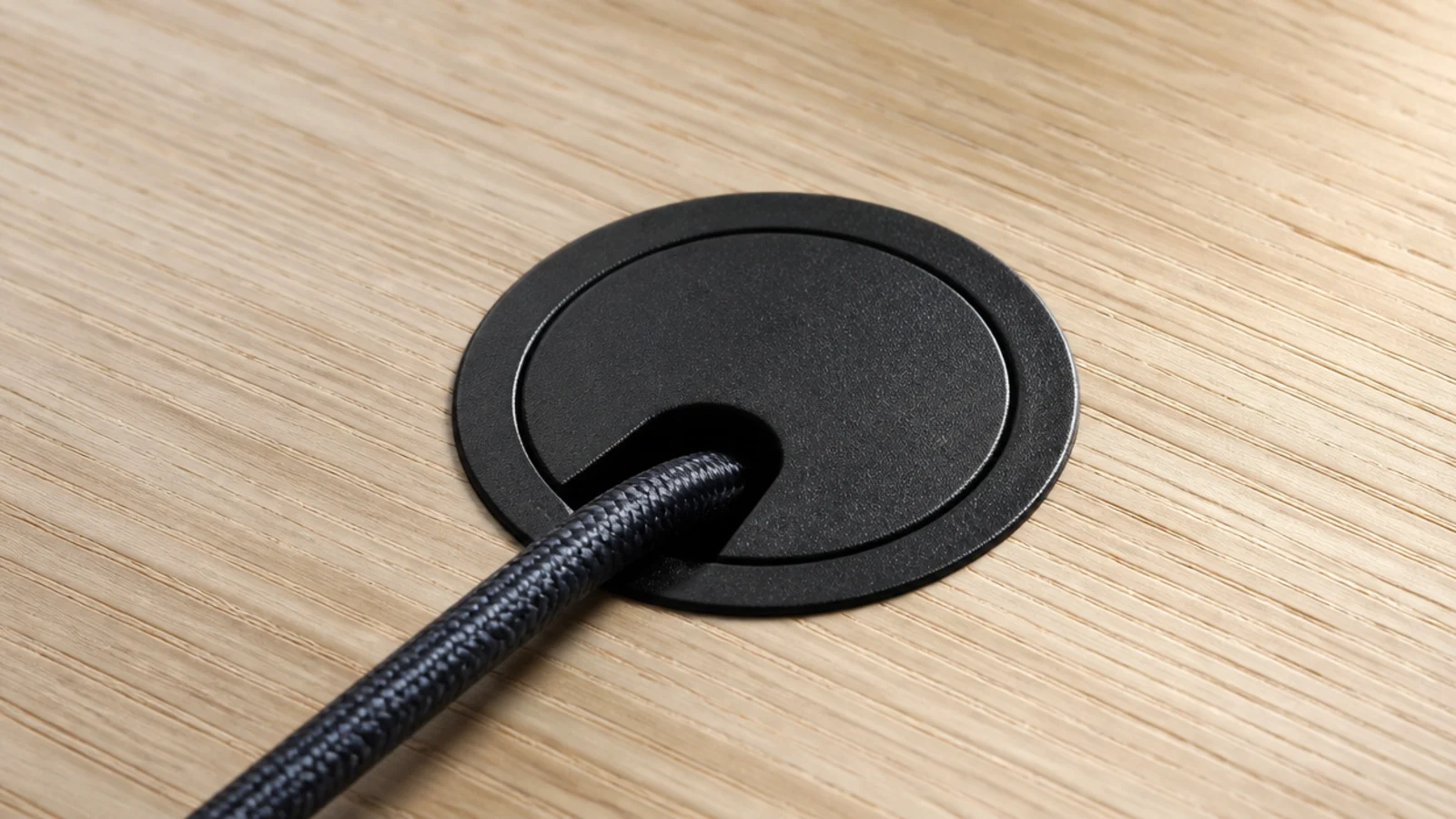 one cable passing neatly through a flush grommet in a desk