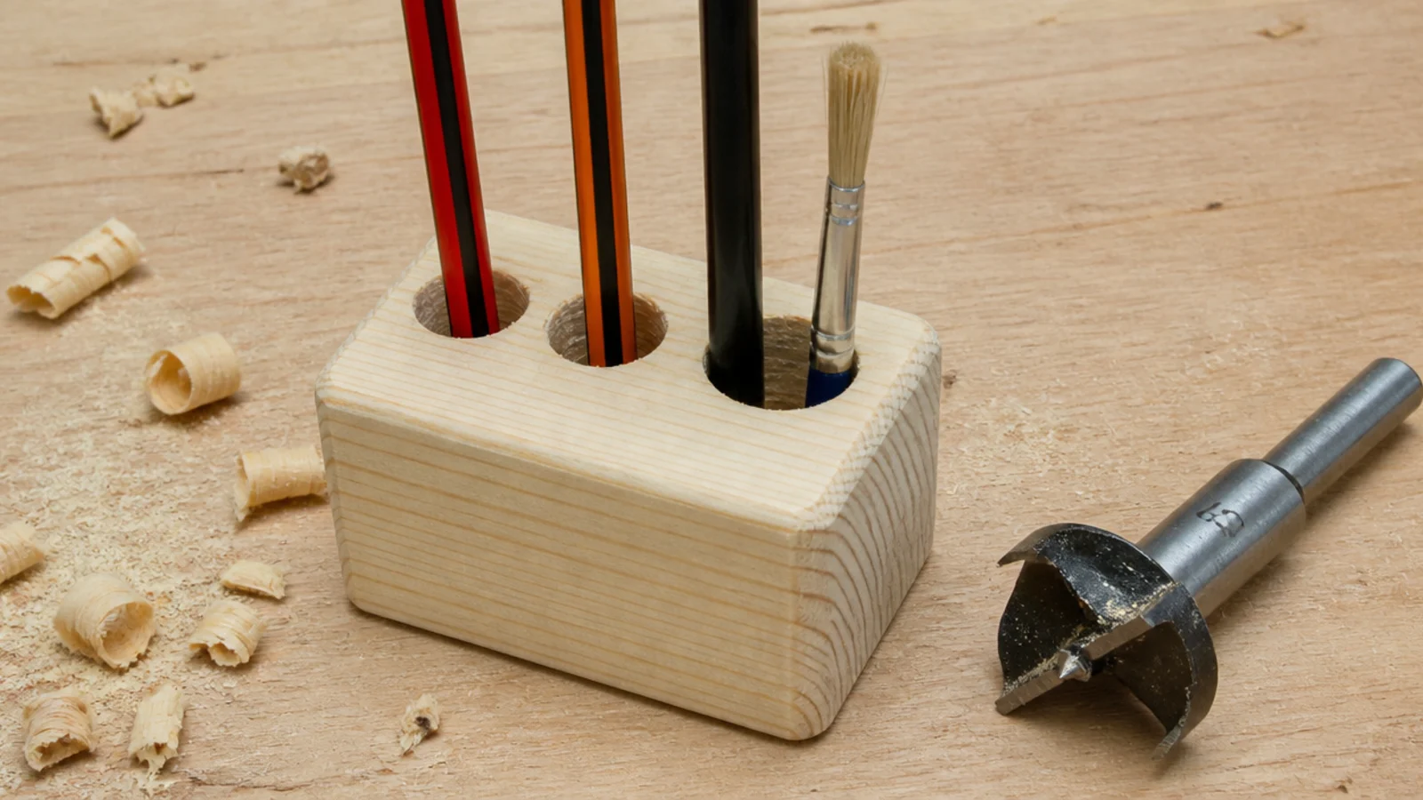 pine offcut block drilled with three holes holding pens upright