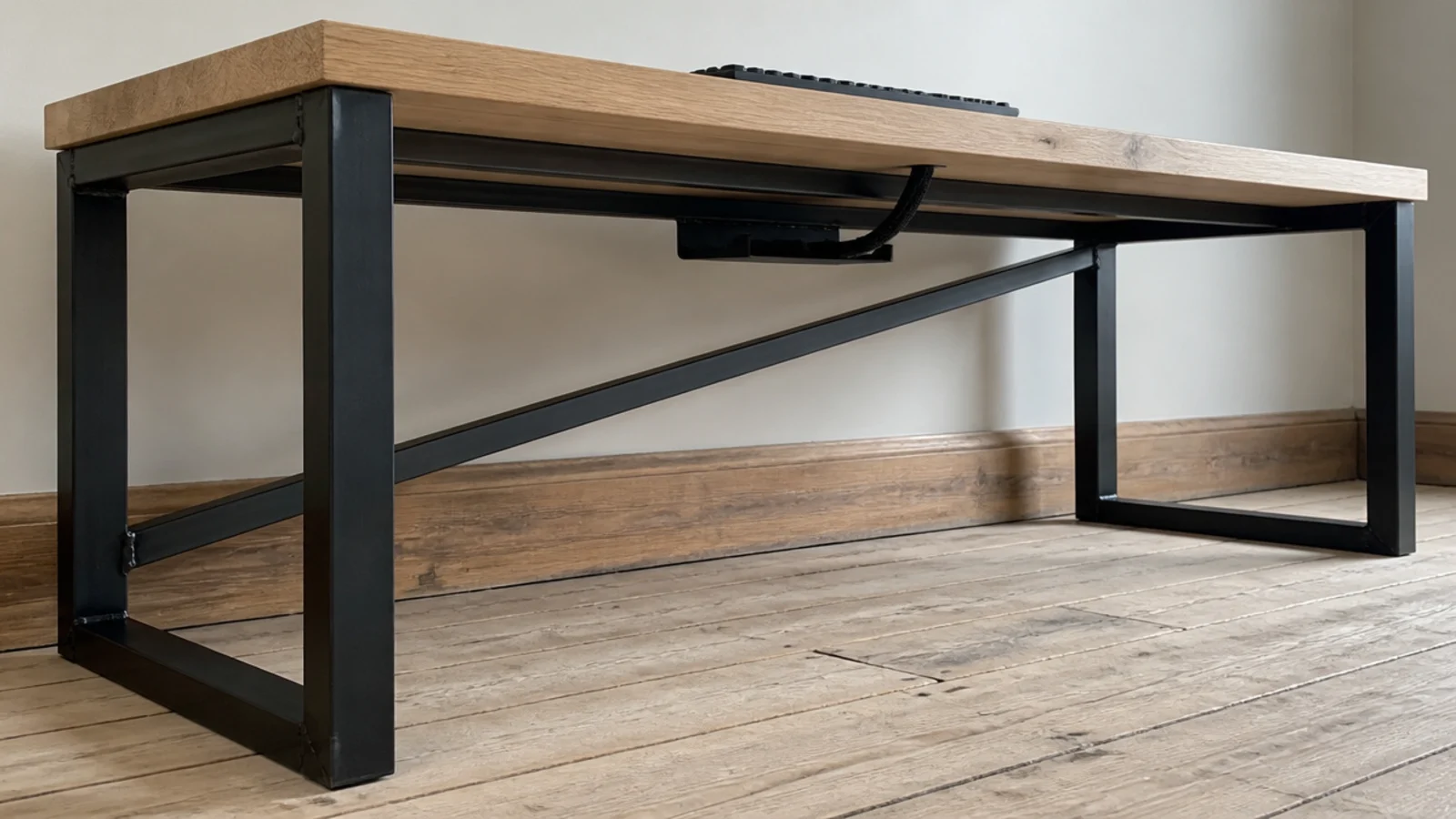 welded steel desk frame supporting a thick pale timber work surface