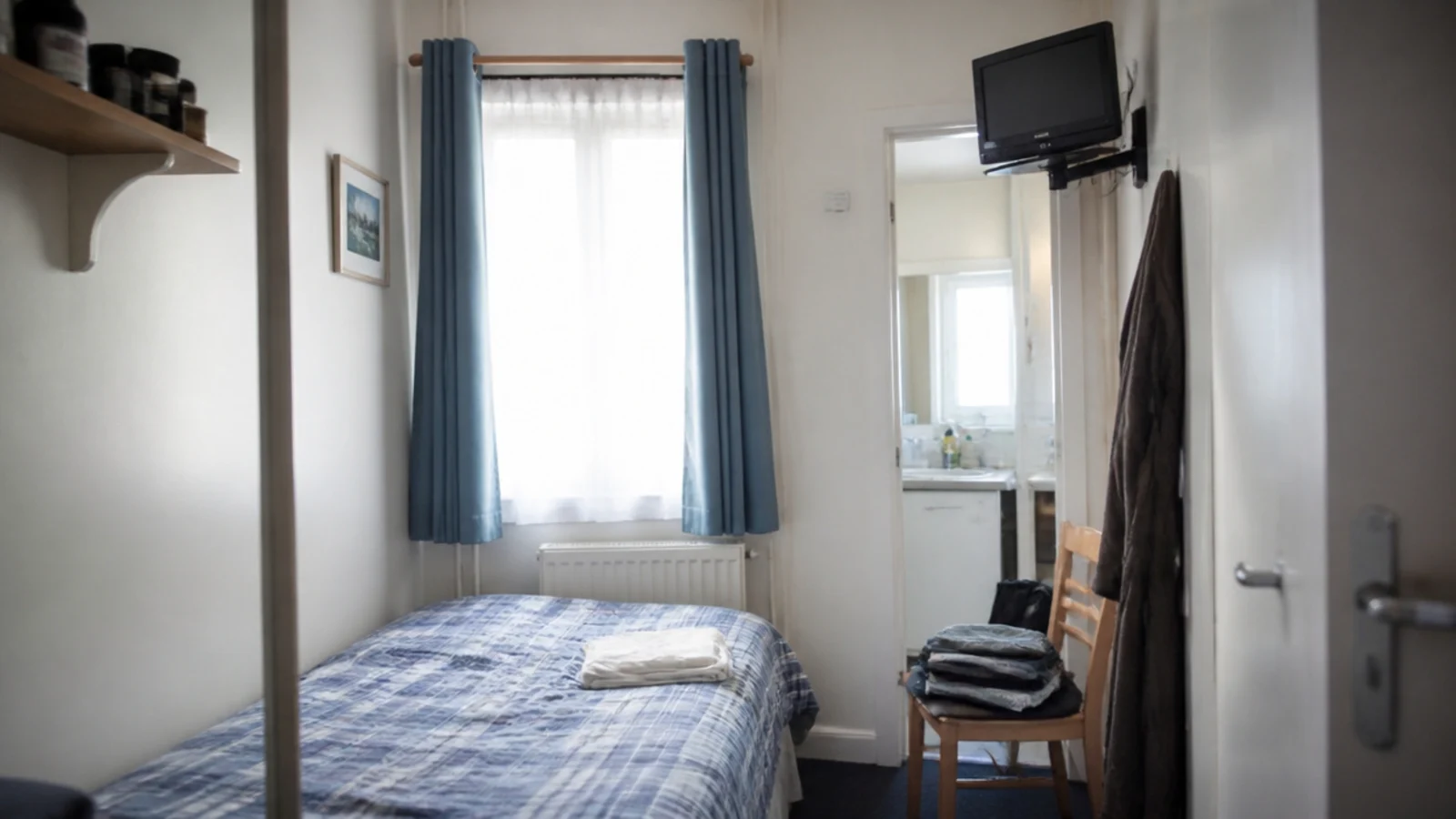 small screen sitting high on a bracket in a very small bedroom