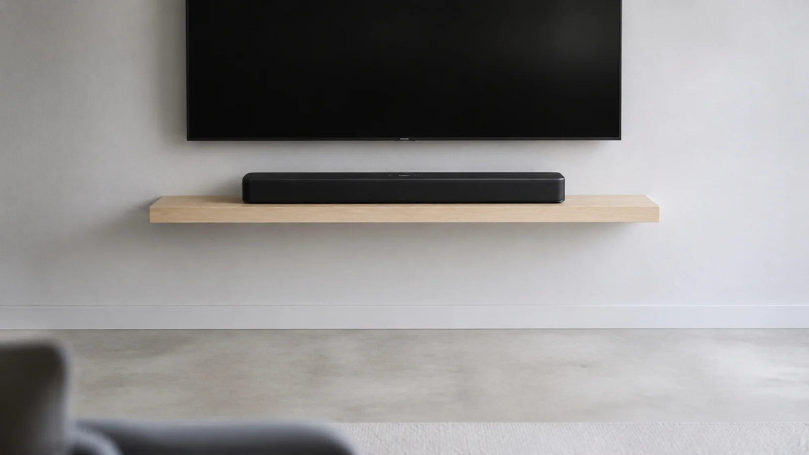 single narrow floating shelf carrying a soundbar under a screen