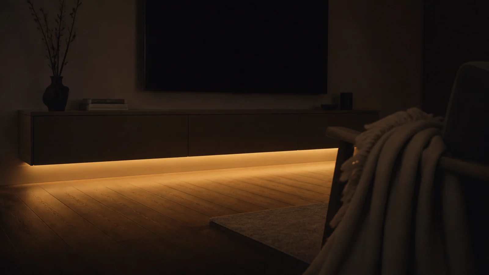 warm light spilling from under a media unit onto a wooden floor