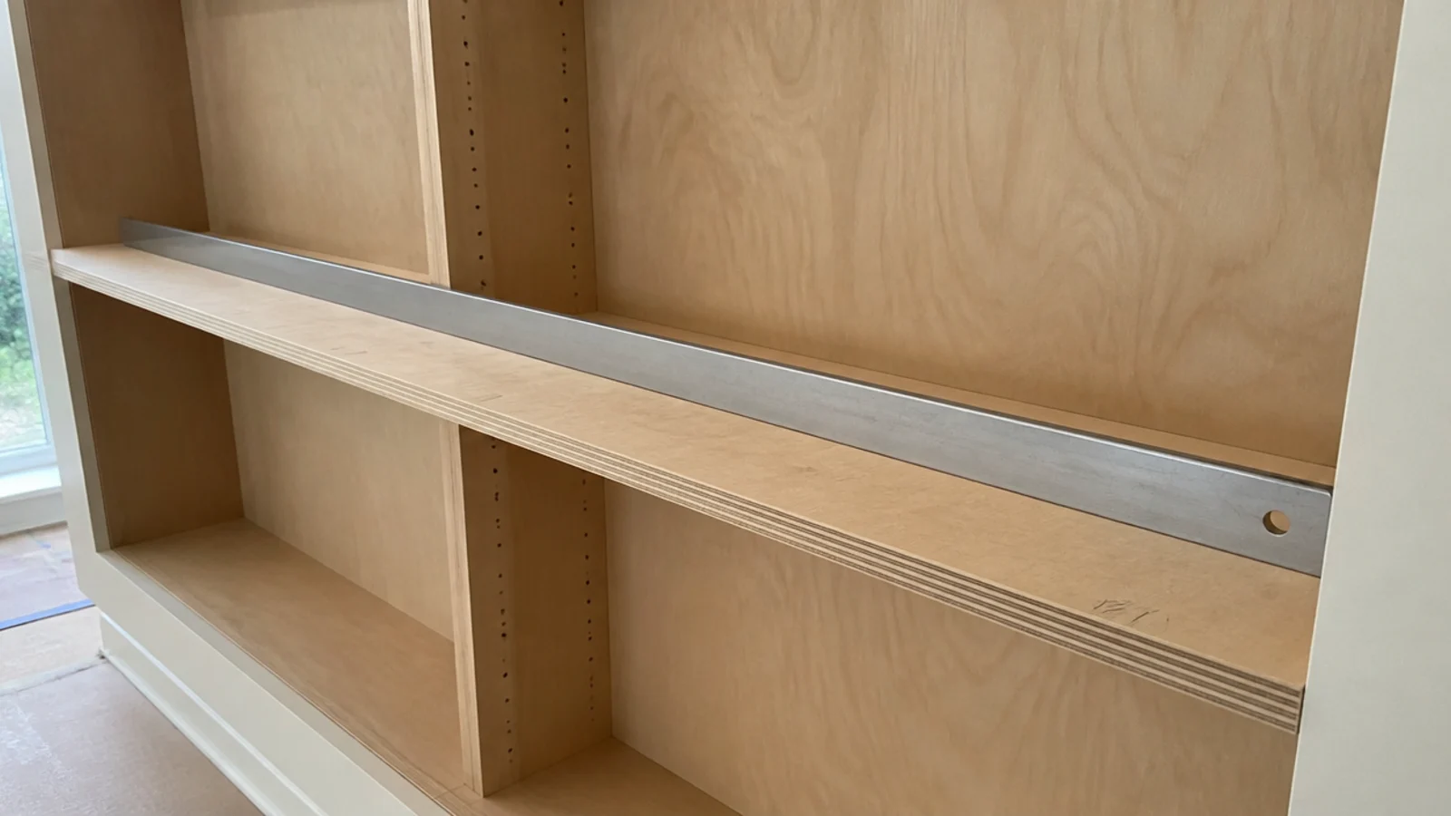 long plywood shelf resting in place with a straight edge across it