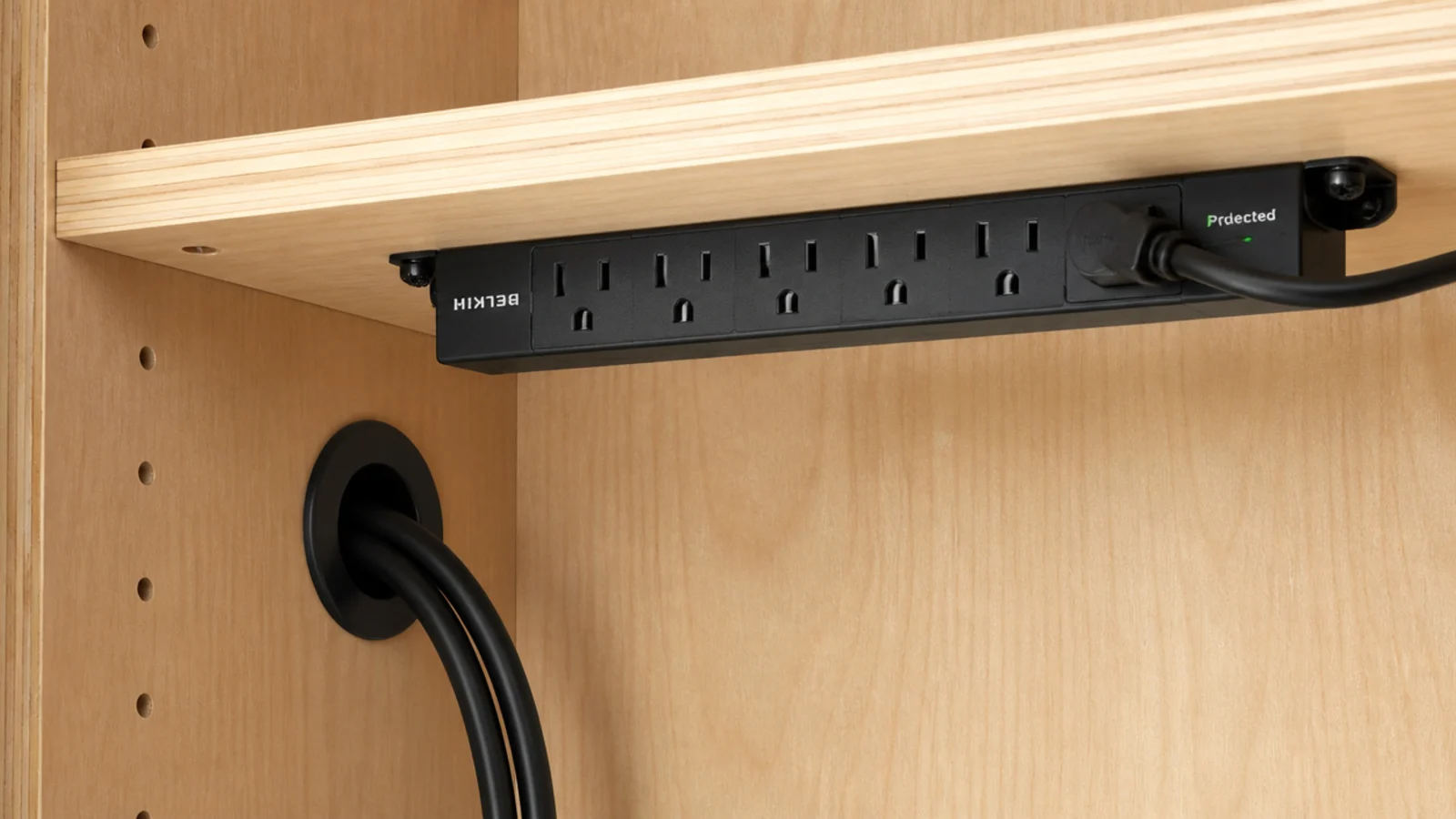cables threaded through a grommet with a power strip fixed inside